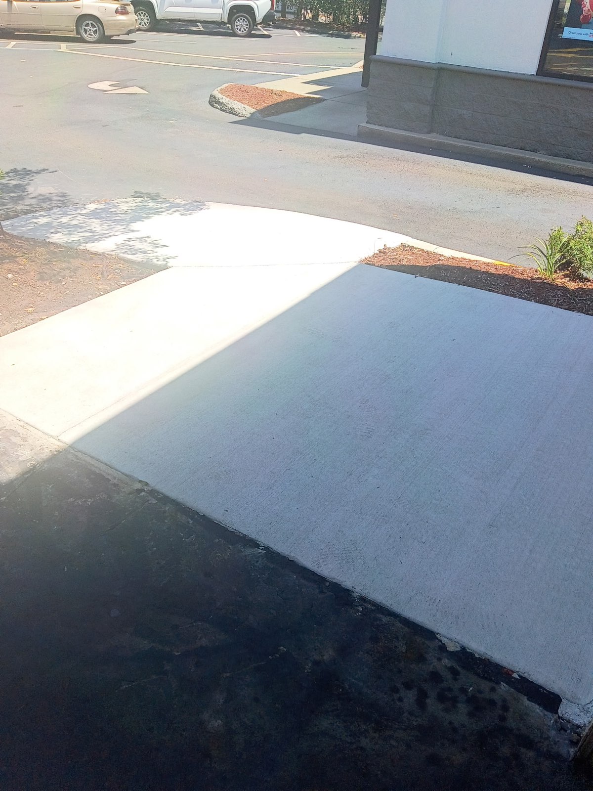 Fresh broom-finished concrete pad, level with the surrounding asphalt