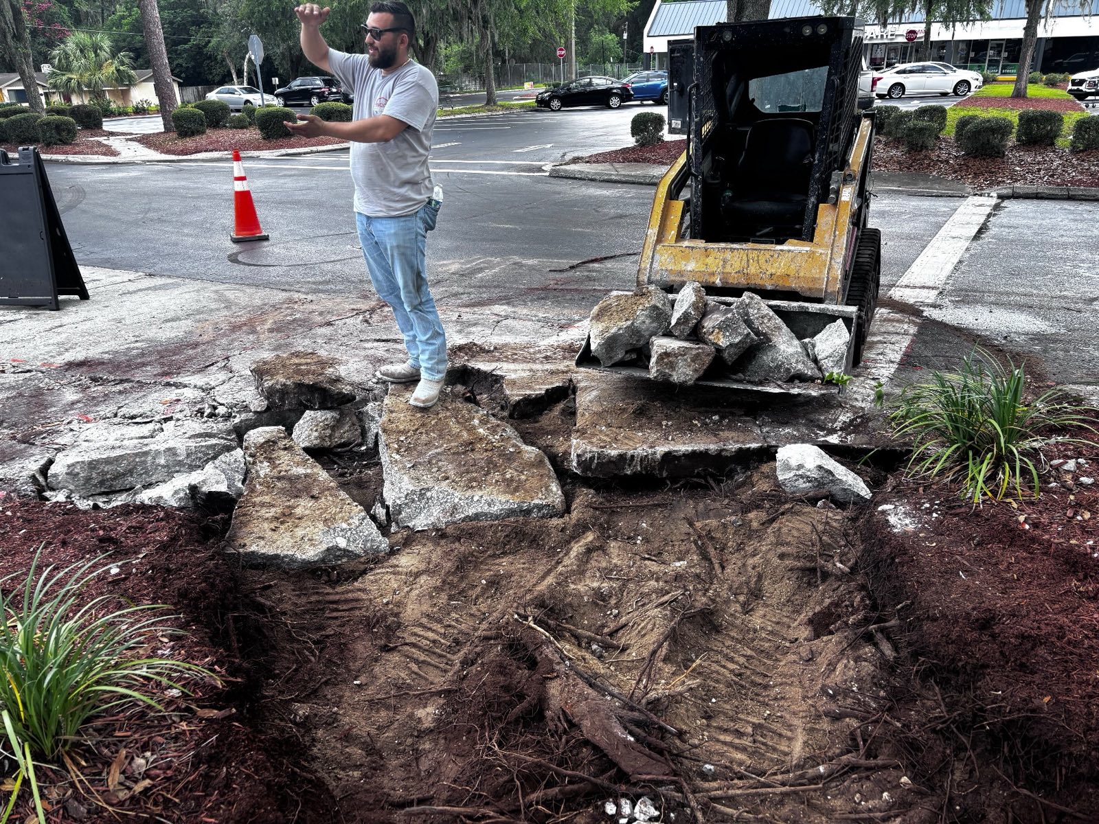 Crew removing broken concrete slabs down to solid base with a skid steer